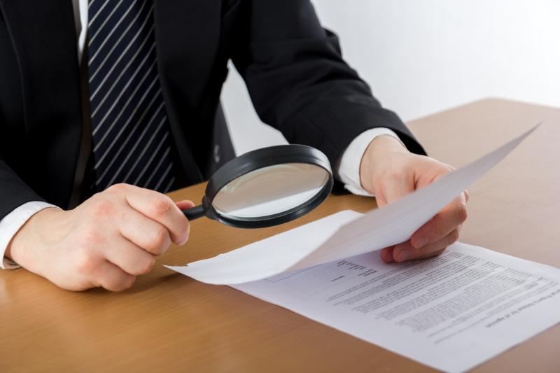 A man with magnifying glass on a contract.